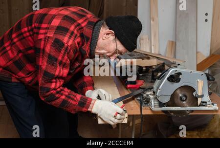 Senior man works as a carpenter in his workshop. Active old age Stock Photo