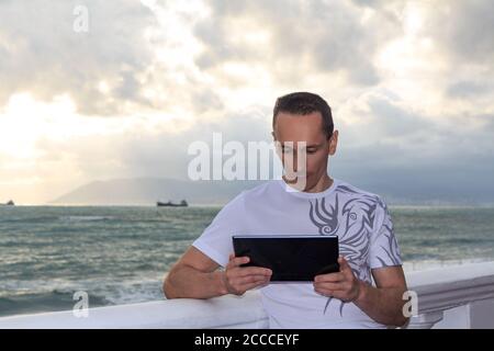 A man with a tablet on the embankment Stock Photo