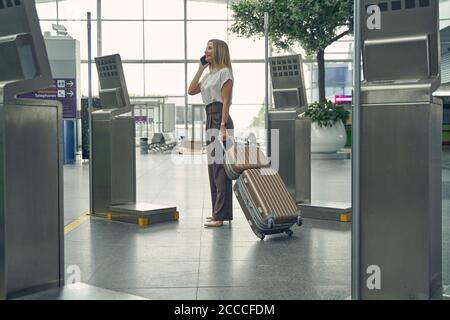Pleased young woman checking arrival and departure monitor Stock Photo