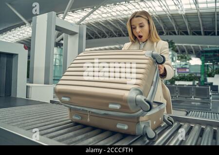 Emotional blonde female person checking her suitcase Stock Photo