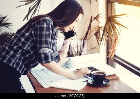 Architect workspace concept, Architects Asian woman working with blueprints construction plans , smartphone and tablet in the office, Vintage style. B Stock Photo