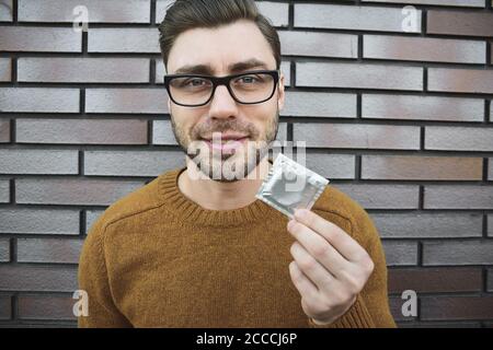 Male youngster with appealing look, holds condom. Stock Photo