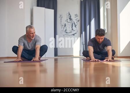 Two yogis doing a forward bend exercise Stock Photo
