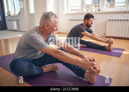Beginner yogi and his coach practicing yoga Stock Photo