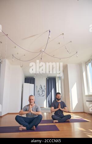 Two flexible men doing a lotus pose Stock Photo