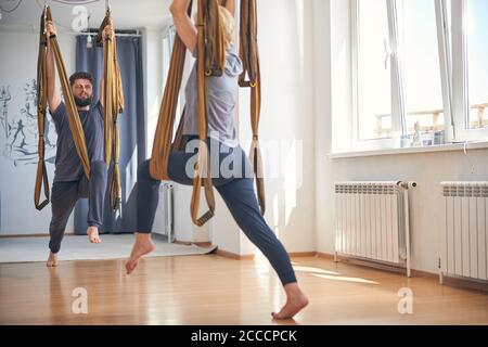Dark-haired yoga teacher and his student exercising together Stock Photo