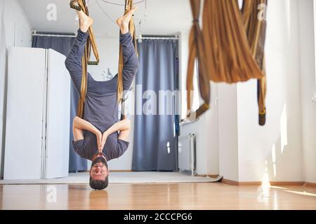 Fit man doing an aerial yoga headstand Stock Photo