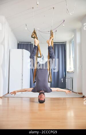 Strong sporty young man doing anti-gravity yoga Stock Photo