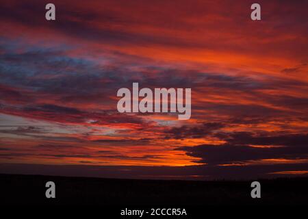 Landscape of the Dutch Wadden Isle Schiermonnikoog. Dramatic colored red sky with clouds. Stock Photo