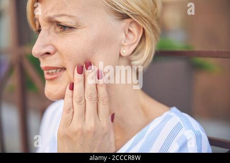 Low-spirited short-haired lady experiencing an acute toothache Stock Photo
