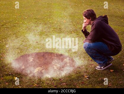 Man contemplating a giant hole with smoke coming out from it Stock Photo
