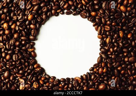Coffee beans are scattered over the surface on a blank white background. a handful of brown coffee beans. Coffee background with copy space for an Stock Photo