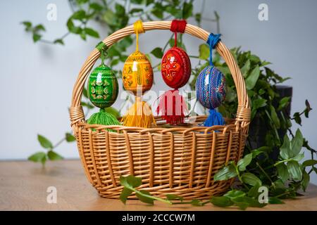 Hand painted Easter eggs, made of wood in a brown basket – decoration of a holiday table during celebration Stock Photo
