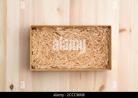 Gift box with decorative straw on wooden table, top view Stock Photo