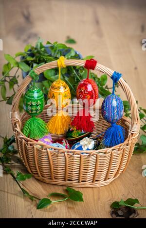 Colorful hand painted Easter eggs, made of wood in a brown basket – decoration of a holiday table during celebration Stock Photo