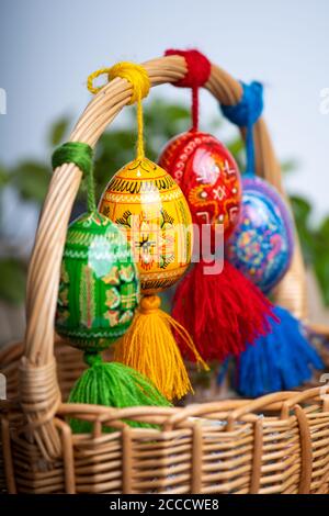 Four beautiful hand painted Easter eggs, made of wood in a brown basket – decoration of a holiday table during celebration Stock Photo