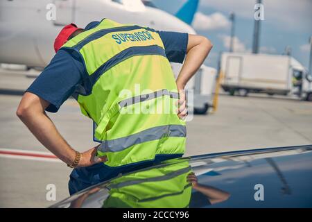 Airport male worker bent double from an acute pain Stock Photo