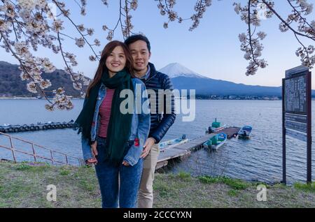 Lovely couple taking photo at Kawaguchiko with Fuji mountain and cherry blossoms view in spring, Japan. Stock Photo