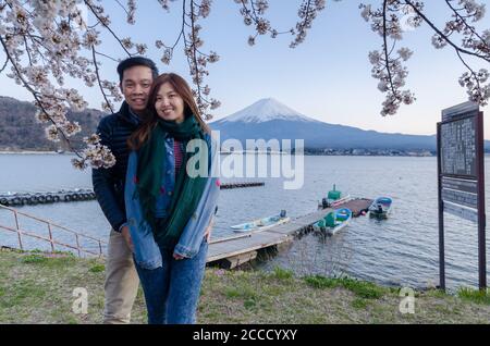 Lovely couple taking photo at Kawaguchiko with Fuji mountain and cherry blossoms view in spring, Japan. Stock Photo
