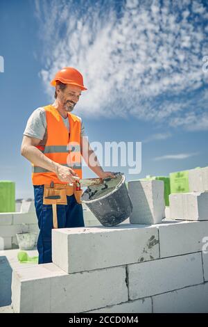 Bricklayer in a hard hat laying bricks outdoors Stock Photo