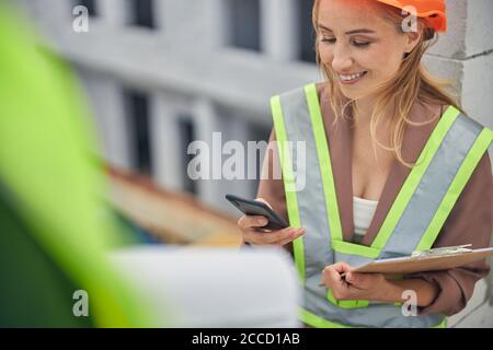 Cute young female worker using her gadget Stock Photo