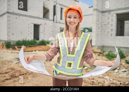Young woman in a helmet holding a home plan Stock Photo