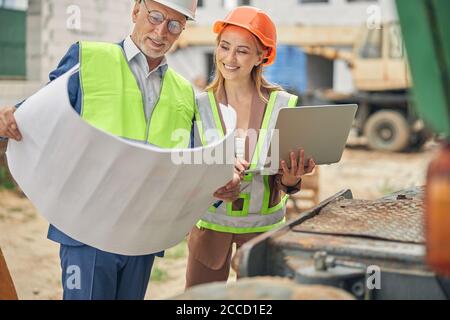 Woman with a laptop looking at her colleague house plan Stock Photo