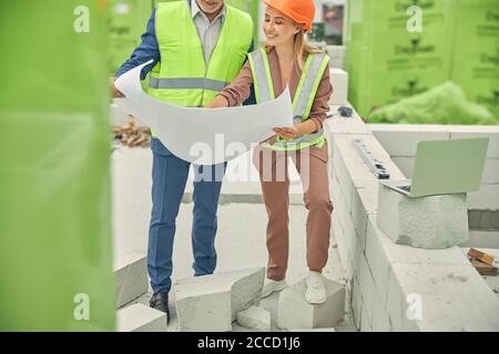 Joyous business lady examining a technical drawing with a builder Stock Photo