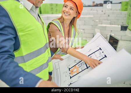 Joyful businesswoman analyzing a technical drawing with a foreman Stock Photo