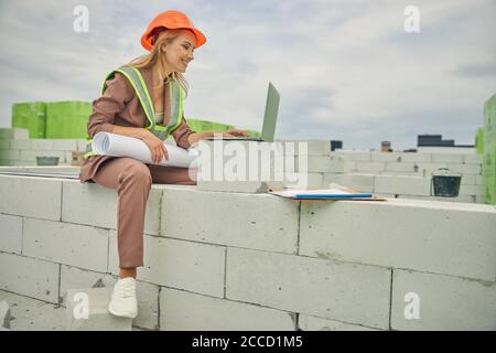 Pleased woman with drawings sitting on the bricks Stock Photo