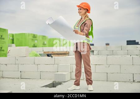 Beautiful young woman engineer holding home plans Stock Photo