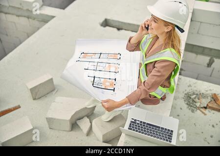 Pleased construction manager calling on her smartphone Stock Photo