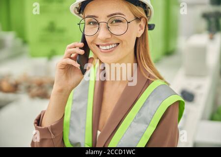 Smiling female engineer talking on her smartphone Stock Photo