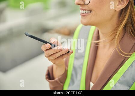 Smiling pleased female in workwear standing outdoors Stock Photo