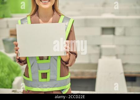 Smiling female builder dressed in workwear standing outdoors Stock Photo