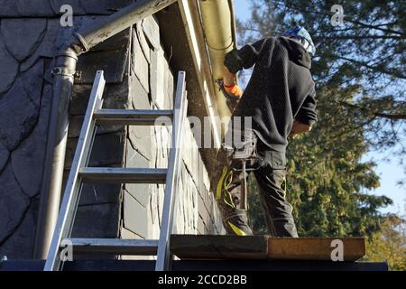 Low angle shot of a construction worker working and fixing a roof Stock Photo