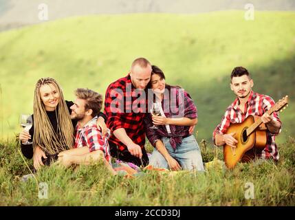 Spending summer day. group of people spend free time together. family camping. hiking adventure. happy men and girls friends with guitar. friendship. romantic picnic in tourism camp. campfire songs. Stock Photo