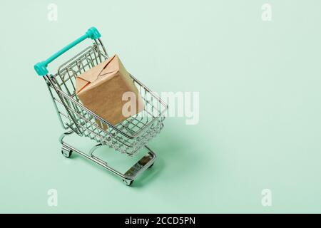 Shopping cart with package boxes on green background. Shopping and delivering concept. Stock Photo