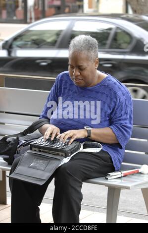 Austin, TX  USA, April 23, 2007: An African-American shopper types on her 'BrailleNote' machine, similar to a Personal Digital Assistant (PDA) for blind people, at an upscale shopping center in Austin. ©Bob Daemmrich Stock Photo
