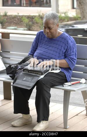 Austin, TX  USA, April 23, 2007: An African-American shopper types on her 'BrailleNote' machine, similar to a Personal Digital Assistant (PDA) for blind people, at an upscale shopping center in Austin. ©Bob Daemmrich Stock Photo