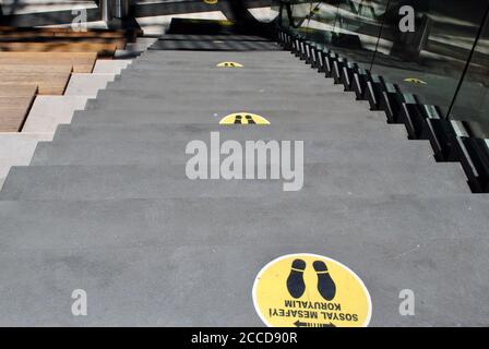 Yellow marking on stairs in order to guide social distancing due to coronavirus or covid-19 pandemic.  Stock Photo