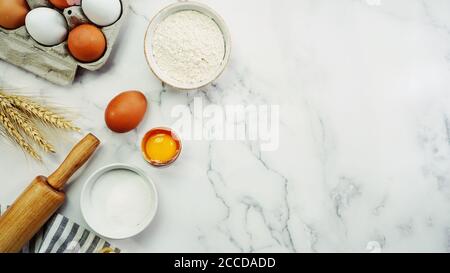Ingredients for baking - Flour,sugar,eggs,milk, rolling pin on white marble background with copy space Stock Photo
