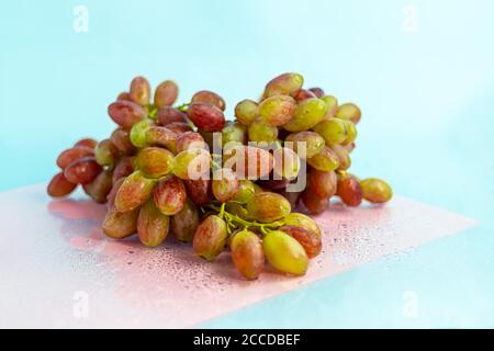 Large and light, wine grapes. It is covered with a white coating called yeast. Glasses are filled with light wine. Water drops on berries. On a multi- Stock Photo