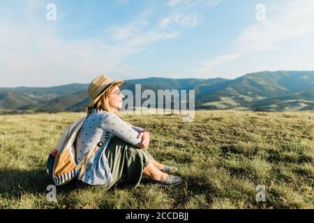 Hiking in mountains. Woman enjoying hike on sunny vacation day. Female with  backpack walking close to waterfall. Spending summer vacation close to  nature - a Royalty Free Stock Photo from Photocase