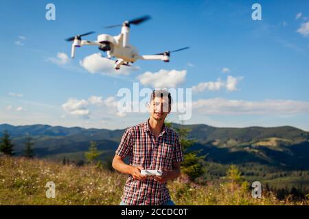 Drone remote control. Man operating copter controller in mountains. Aerial video shooting of summer Carpathins Stock Photo