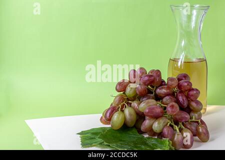 Large and light, wine grapes. It is covered with a white coating called yeast. Glasses are filled with light wine. Water drops on berries. On a multi- Stock Photo