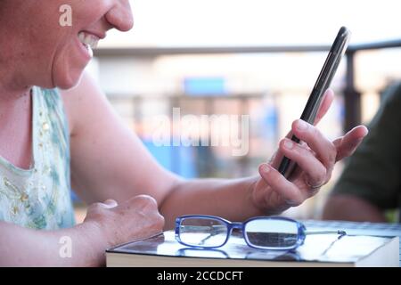 Unrecognizable mature woman watching something on her smartphone and smiling. Diversity and technology concept. Stock Photo