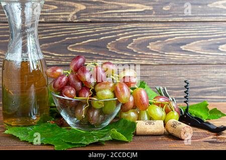Large and light, wine grapes. It is covered with a white coating called yeast. Glasses are filled with light wine. Water drops on berries. On a wooden Stock Photo