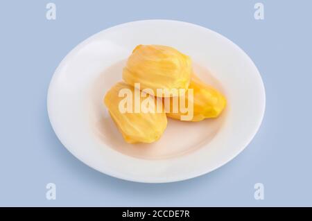Fresh ripe yellow tropical jackfruit on white dish isolated on light blue background, clipping path included. Stock Photo