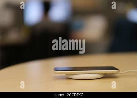 close up one smartphone on wireless charger. blurred office background Stock Photo